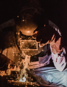 A Welder Wearing A Mask To Protect His Face While Working.